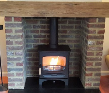 Charnwood C5 Woodburner - in black with a slate and a Bespoke oak beam, air dried. Installed in Holmbury St. Mary near Dorking, Surrey